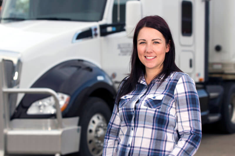 woman truck driver standing in front of her semi truck