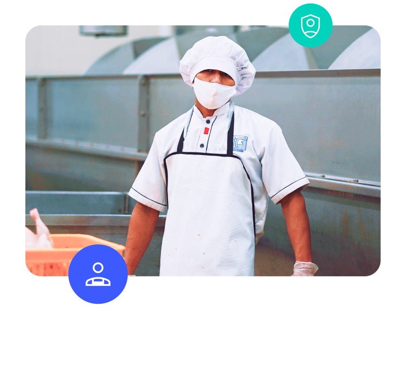 employee wearing hair net, apron, and mask working in a food production facility.