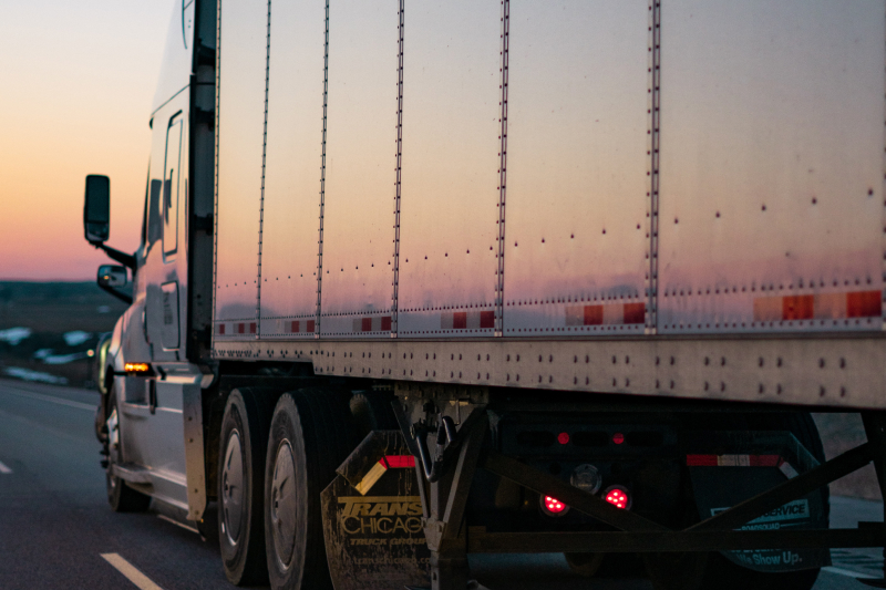 eighteen wheeler tractor trailer driving down the highway at dusk